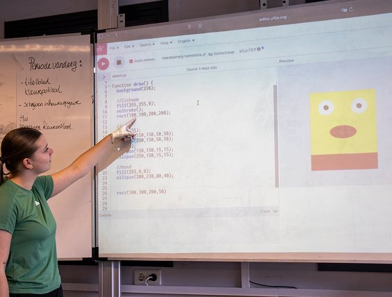 Een docent wijst op het digibord naar de code van een getekend gezichtje in p5.js