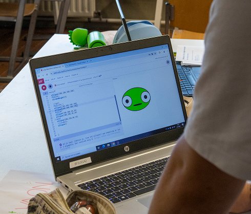 Laptop met p5.js-code en een getekend groen monster op het scherm